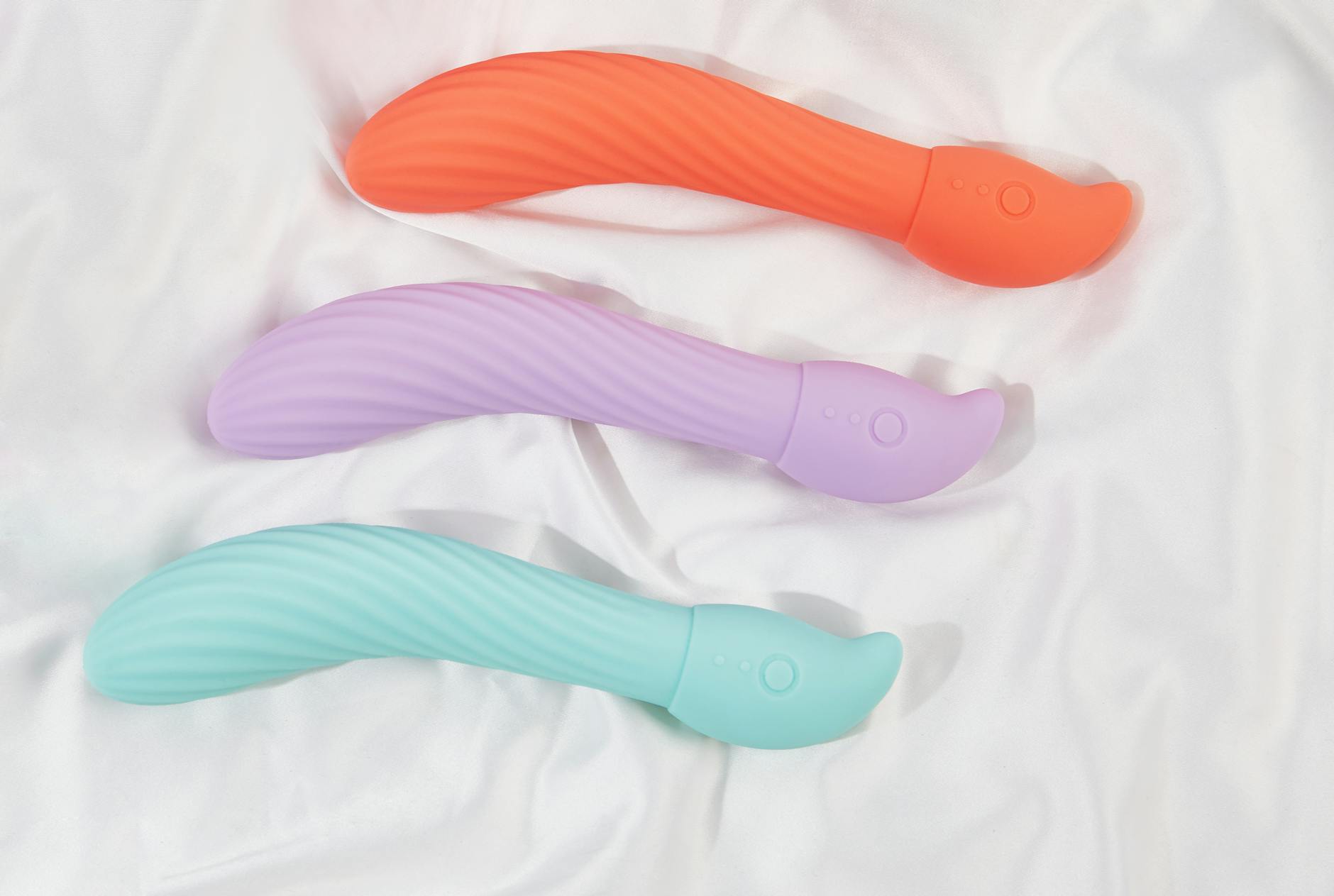 Three colorful vibrators arranged on white fabric, highlighting intimate wellness tools for couples.