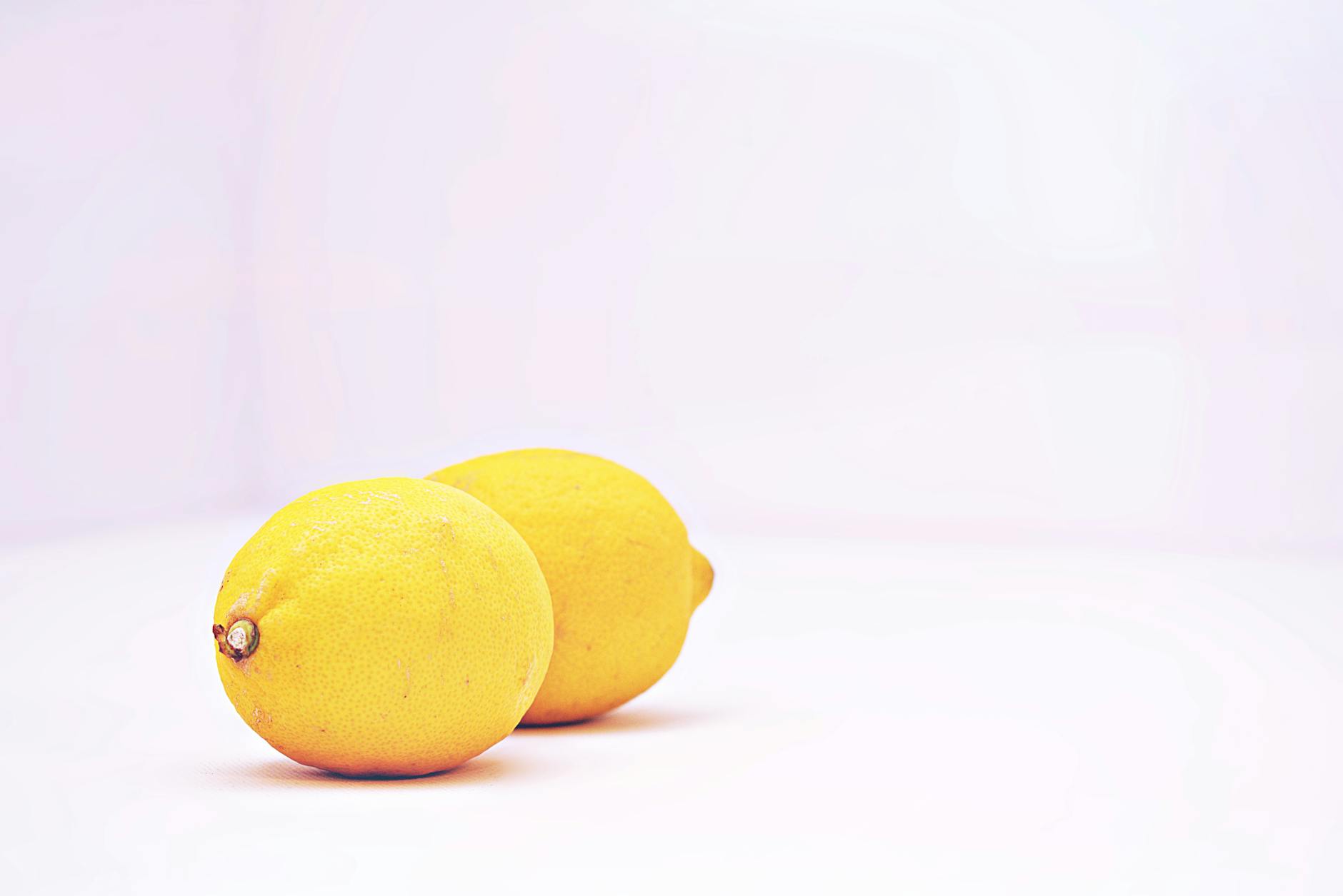Two vibrant lemons against a minimalistic white background, symbolizing freshness and renewed vitality