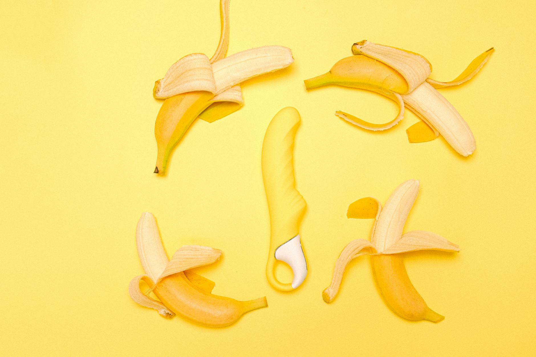 Yellow Lemon clitoral vibrator surrounded by fresh lemons on a bright yellow background