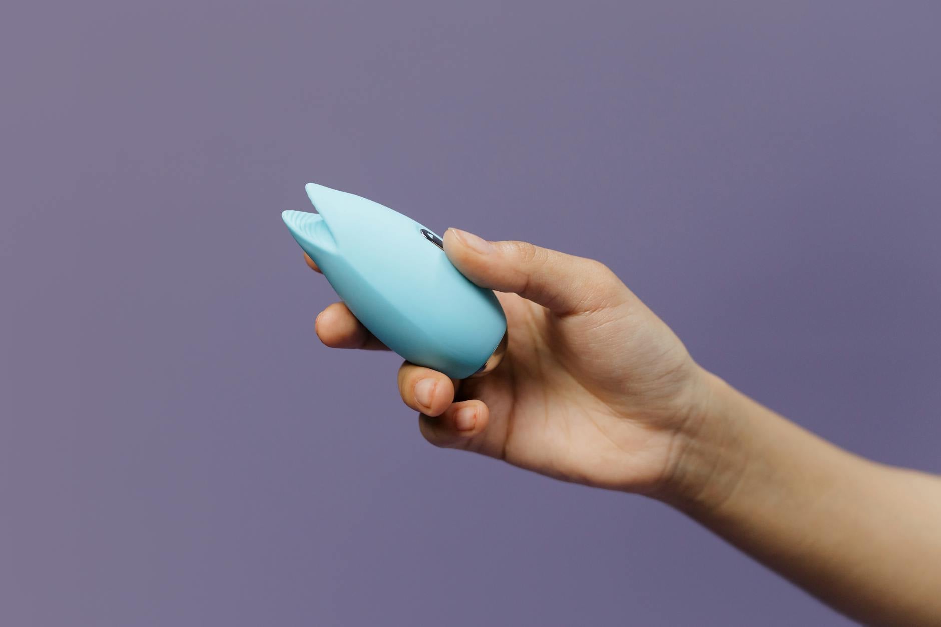 A silicone vibrator held in hand against a purple background, symbolizing reclaiming sensation and pleasure