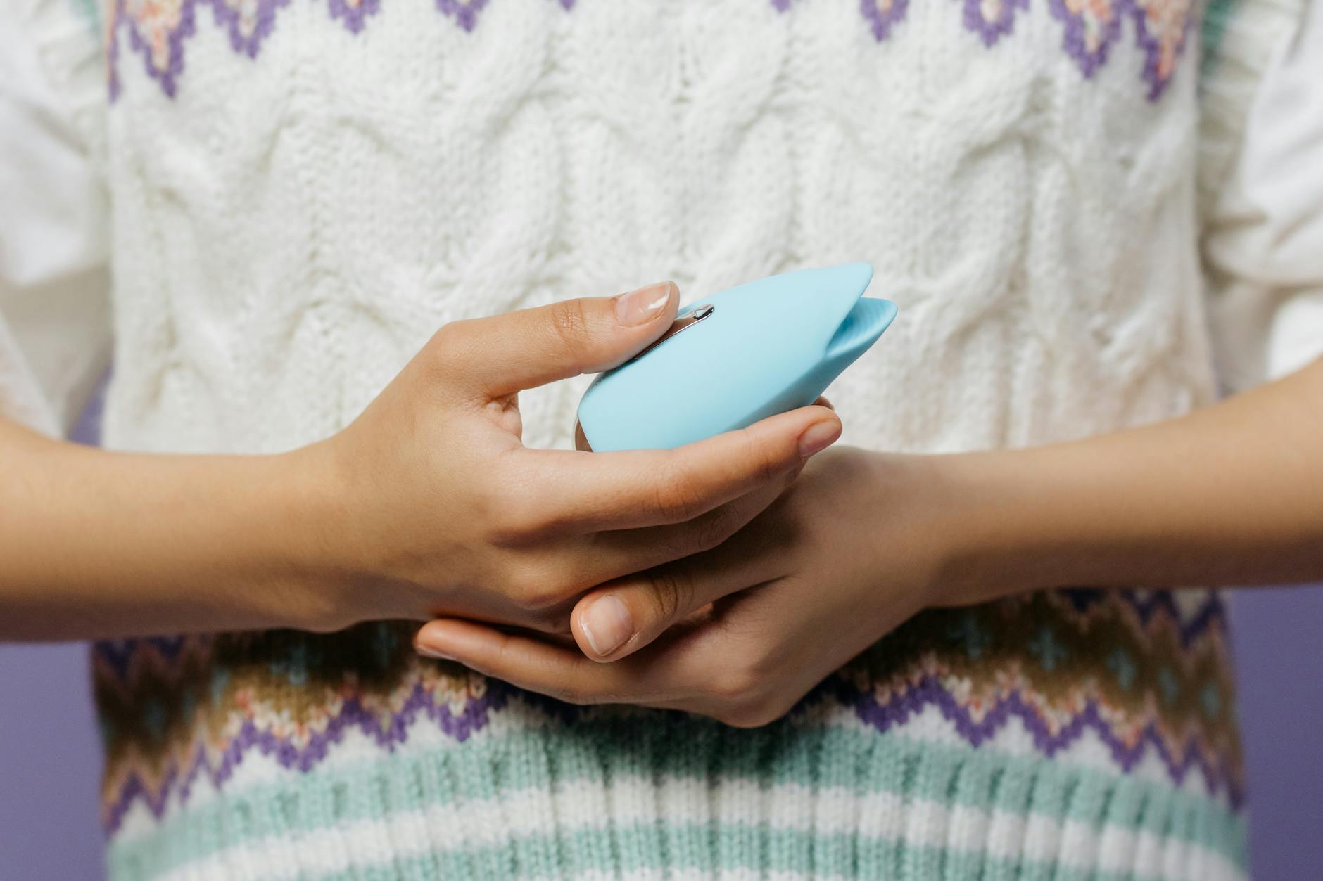Woman holding blue and pink silicone vibrators in contemplative pose, representing pleasure options for sensitive vulvas.