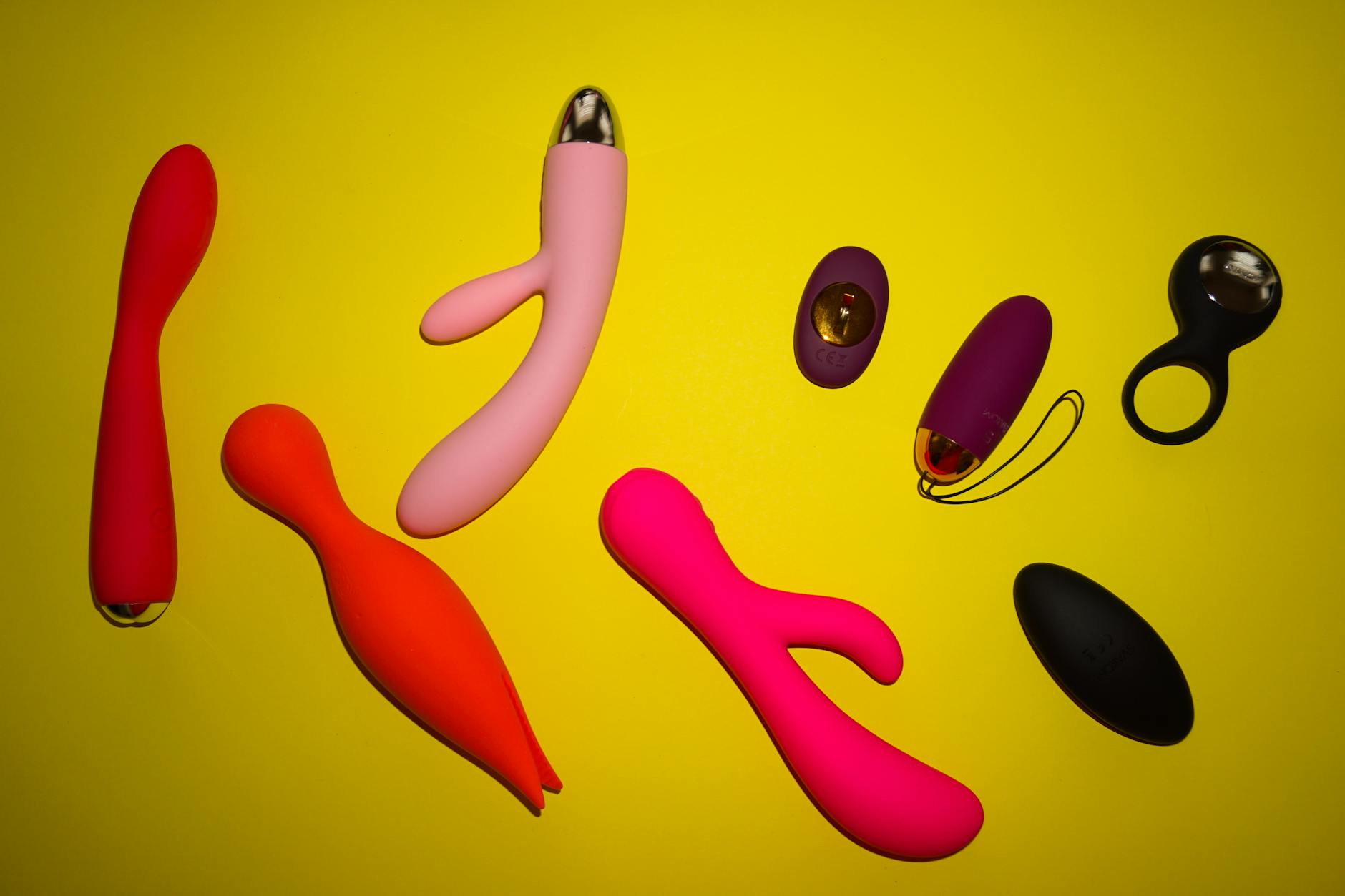 Disposición vibrante de juguetes sexuales variados sobre una superficie amarilla brillante, mostrando diversidad y diseño